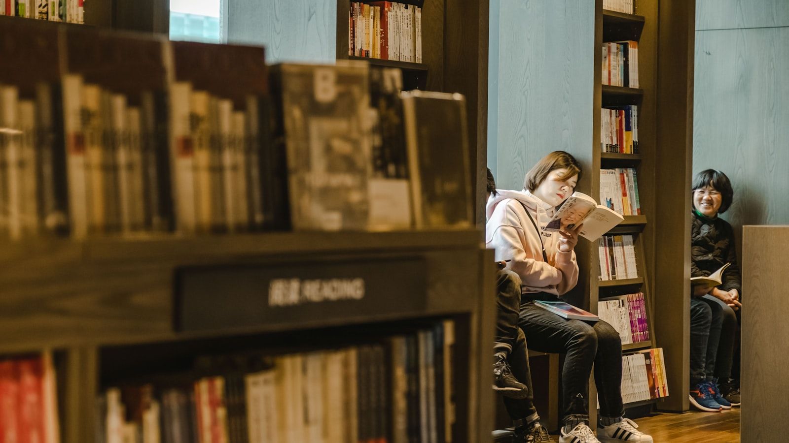 Une lectrice debout devant les rayonnages d’une bibliothèque